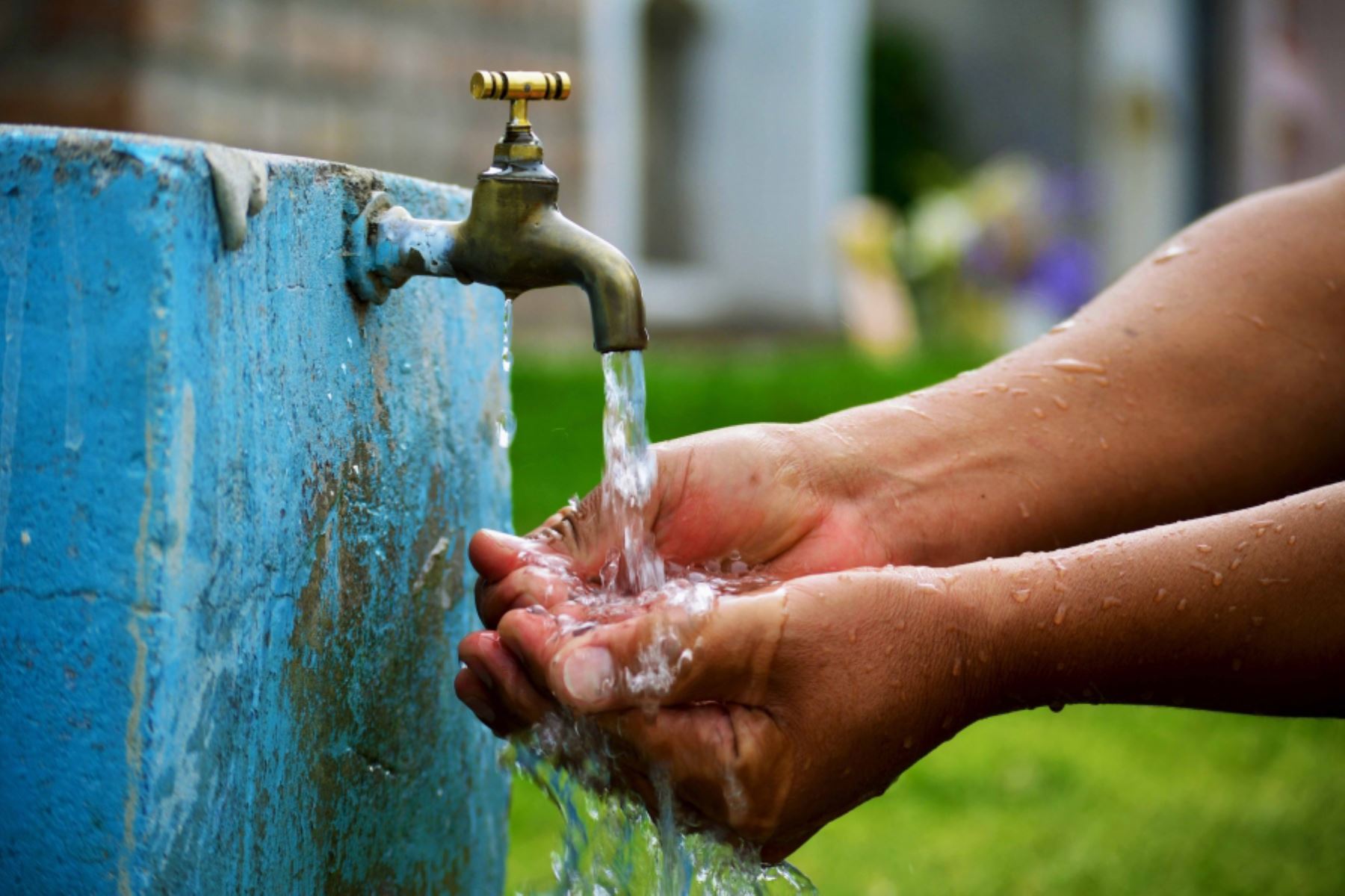 manos recibiendo agua que sale de una grifería